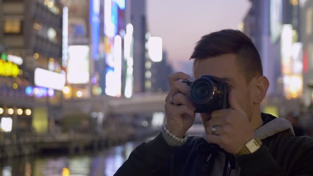 International tourist taking photos of the neon lights in Japan.