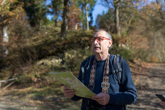 Older looking into nature with map in forest