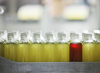 Closeup of bottles with lemon flavoured water on a bottling plant production line. With one red bottle used as a marker.