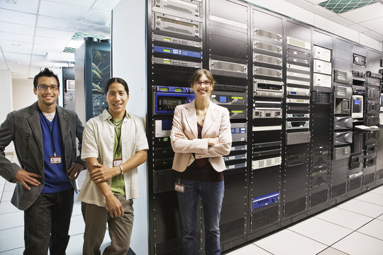 Portrait of three multi-ethnic technicians who work in a large computer server room.