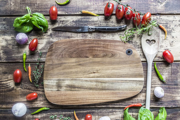 Holzbrett mit Kochlöffel, Messer und Kochzutaten