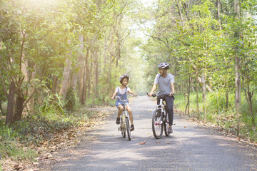 Happy father and daughter cycling in the park, togetherness relaxation concept