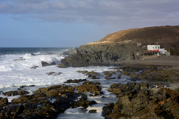 Weißes Haus an einer Felsenküste.