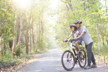 Obraz premium Happy father and daughter cycling in the park, togetherness relaxation concept