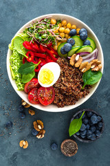 Buddha bowl dinner with boiled egg, chickpea, fresh tomato, sweet pepper, cucumber, savoy cabbage, red onion, green sprouts, spinach leaves, blueberry, walnuts, chia and quinoa