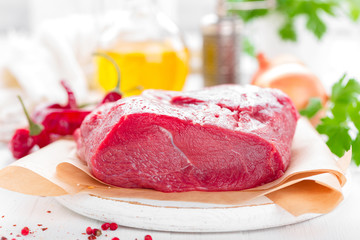 Raw beef meat tenderloin on white background with cooking ingredients closeup. Fresh beef meat on kitchen table
