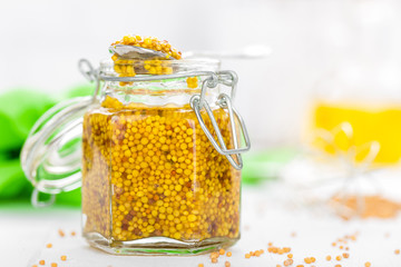 Mustard in glass jar on white wooden table closeup. Dijon mustard