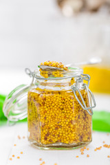 Mustard in glass jar on white wooden table closeup. Dijon mustard