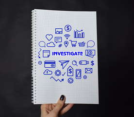 In the hands of a businessman a notebook with the inscription:INVESTIGATE