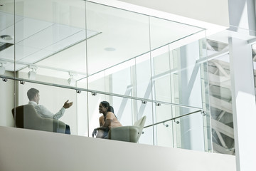 Businessman and woman behind conference room window in large business center