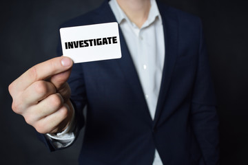 Businessman shows business card with the inscription:INVESTIGATE