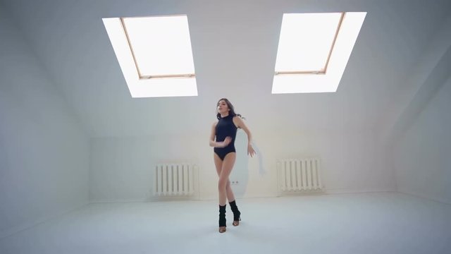 Slender active young girl dancing bachata in the Studio with white walls.