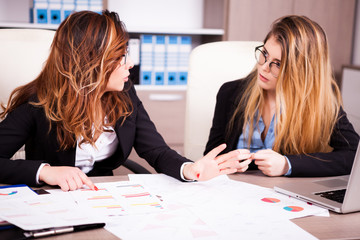 Two colleagues in the office talking at the desk