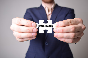 Businessman holding a puzzle with the inscription:INVESTIGATE