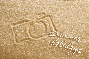 the camera is painted on the sand and the inscription is summer holidays. Beach background. View from above. The concept of summer, summer kanikkuly, vacation, holydays.