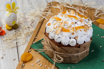 Easter cake (bread) decorated with eggs, candies, dried apricots and sunflower seeds on wooden background. Holidays concept