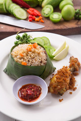 Tutug oncom or fragrant fried rice with fried chicken, tomato, birds eye chilli, cucumber, sambal / red chilli paste, and young mango