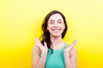 Beautiful woman full of joy and happiness on yellow background in studio