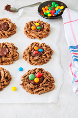 Chocolate bird's nest cookies decorated with colorful candies on a white background.