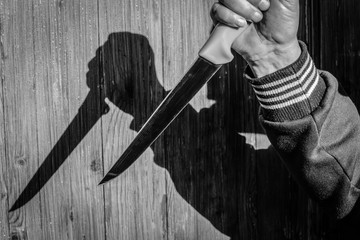 a knife in a mans hand in front of the door, knife attack