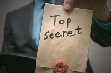Top secret concept. Open the secret. Business man takes out secret documents from his hat....