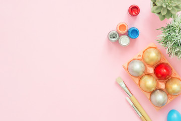 Flat lay top view colorful easter egg painted in pastel colors composition with paint brush on pink pastel color background. Easter day background top view with copy space.