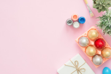 Flat lay top view colorful easter egg painted in pastel colors composition and spring flowers with paint brush on pink pastel color background. Easter day background top view with copy space.