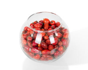 Red berries of briar in large glass bowl, isolated on white