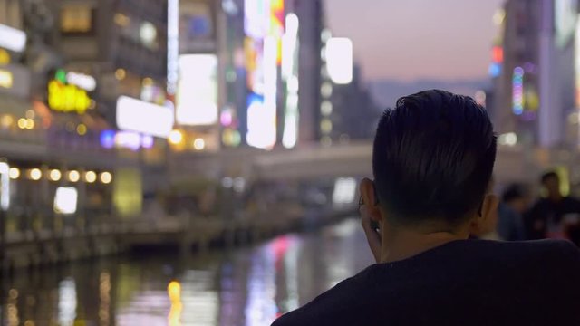 Tourist taking photos of neon lights in Osaka Japan