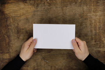 male hands holding a white blank sheet of paper