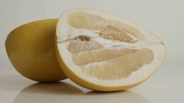 Close-up of Citrus maxima grandis halves tilting footage - Tasty pomello fruit pieces on white