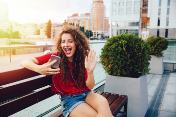 Happy girl having video chat, sitting on bench.