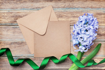 Envelope, hyacinth and ribbon on wooden vintage table top view. Happy Mothers Day holiday greeting card with flowers.