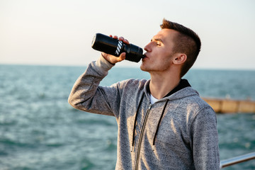 Tired sportsman drinking a water after workout outdoors