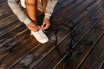 Sportsman tying shoelace on sneakers outdoors