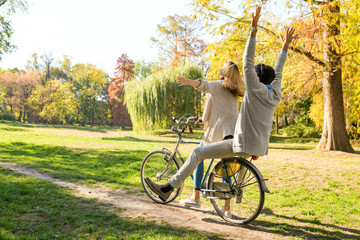 Obraz premium Happy young couple having fun riding a bicycle on sunny day in the park. 