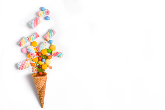 Ice cream cone flat lay image with colorful candy packing into the cone.