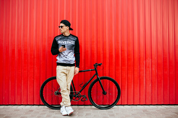 Young hipster man with smartphone, standing near the bike