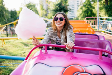 Happy girl holding a cotton candy while riding a roller coaster for children