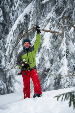 Joyful adventurer with firewood in his hands is walking in snowshoes