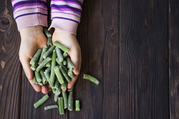 children's hands hold frozen green beans