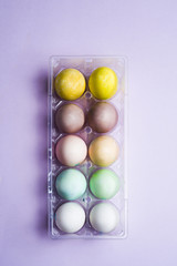 Dyeing eggs for Easter holidays, colored eggs with pastelle color  inside a package over a colored background
