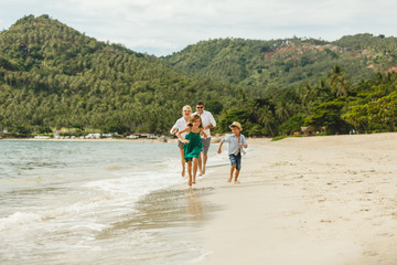 beautiful happy family running by beach on tropical island