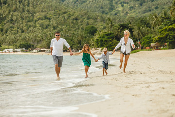 beautiful happy family running by beach and holding hands