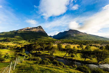 Fototapeta premium Long exposure of mountain with green fields and cloudy blue sky