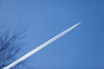 Condensation tracked by the setting sun behind a twin-engine turbojet passenger plane in the March sky