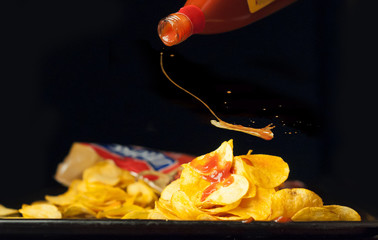 Potato chips with spicy sauce on a black background