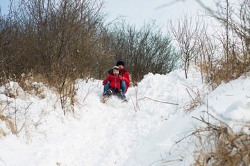 Mother and child sledding in a snowy park
