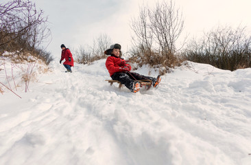 Mother and child sledding in a snowy park
