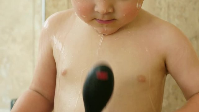 Slow motion of an adorable toddler boy standing in a tile shower